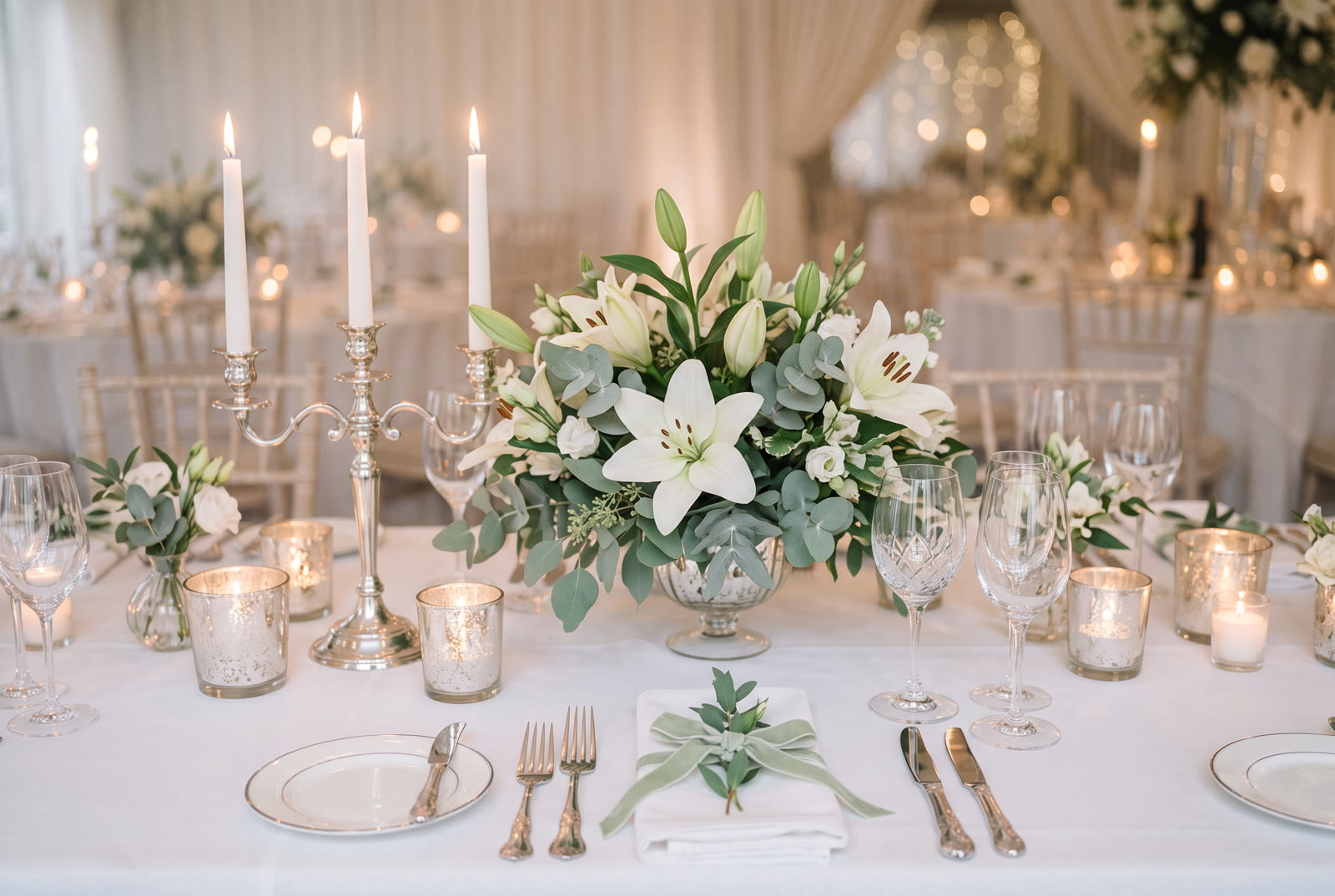 Mesa de recepção com lírios brancos, velas e prata